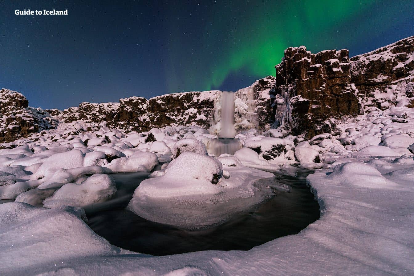 The northern lights glow above Öxarárfoss in Þingvellir National Park on a frosty winter night, southwest Iceland.