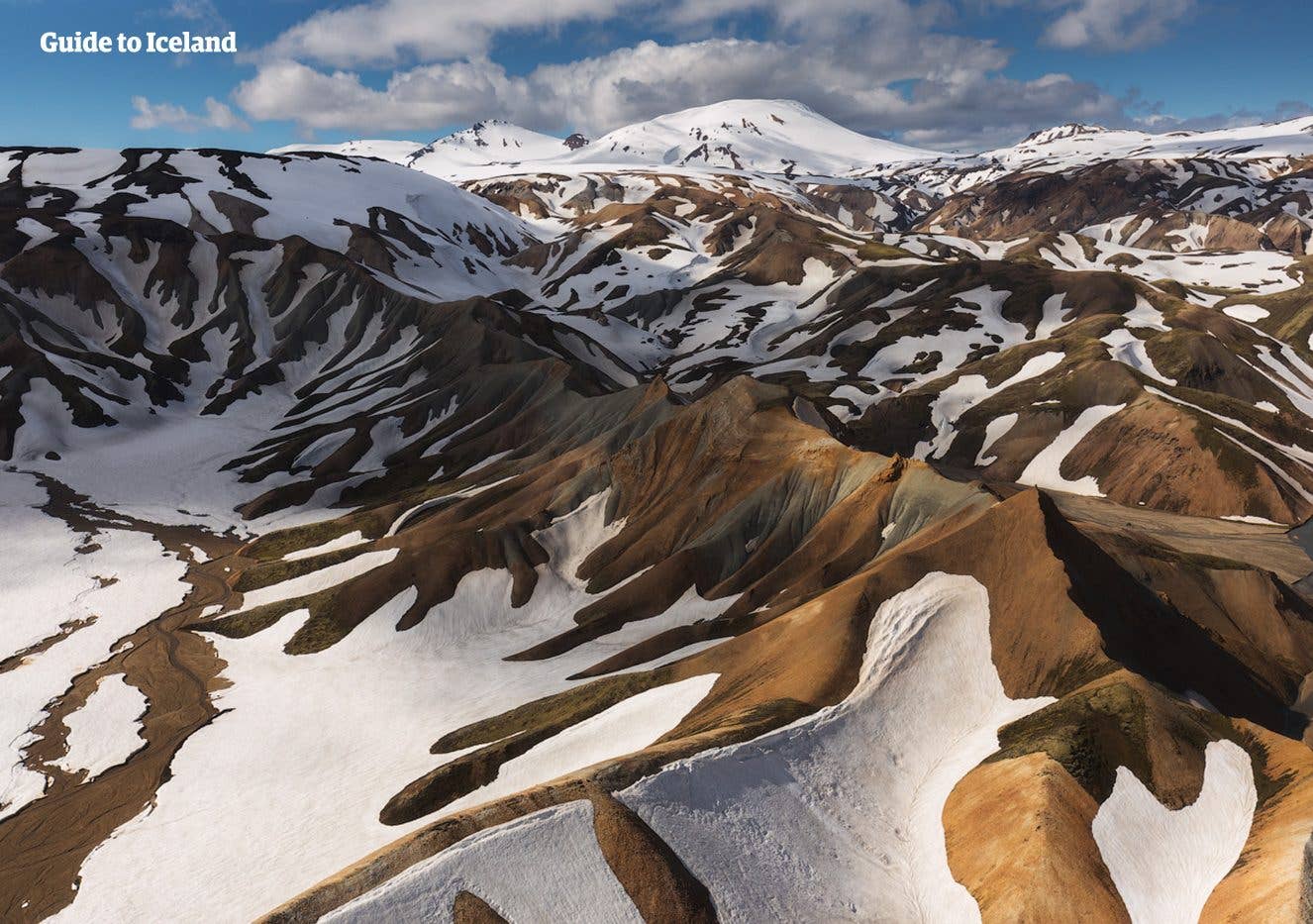 An aerial view of the snow-streaked rhyolite mountains of Landmannalaugar in the Icelandic Highlands.