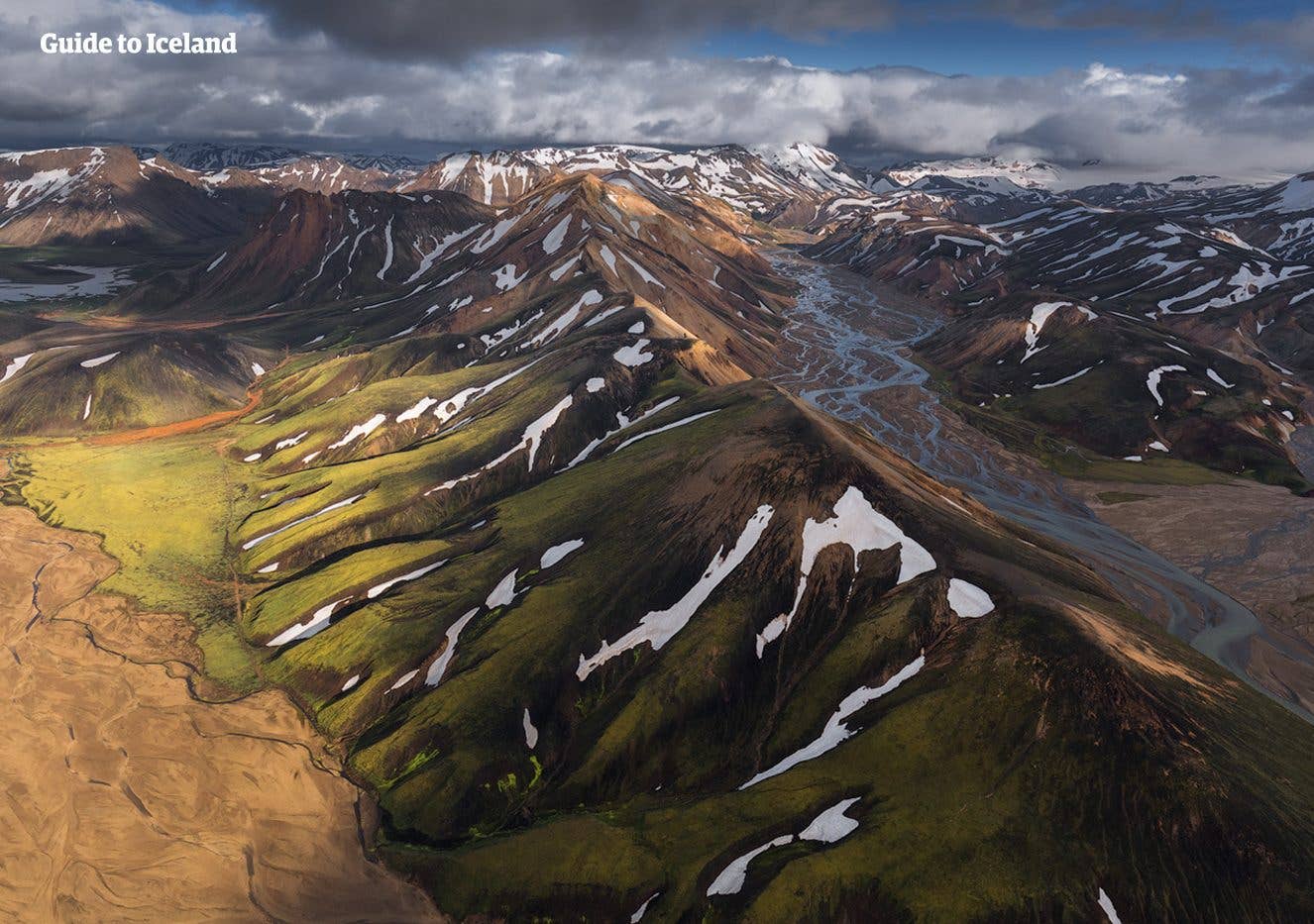 Green and rust-coloured rhyolite ridges surround a braided river in Landmannalaugar, in the southern Highlands of Iceland.