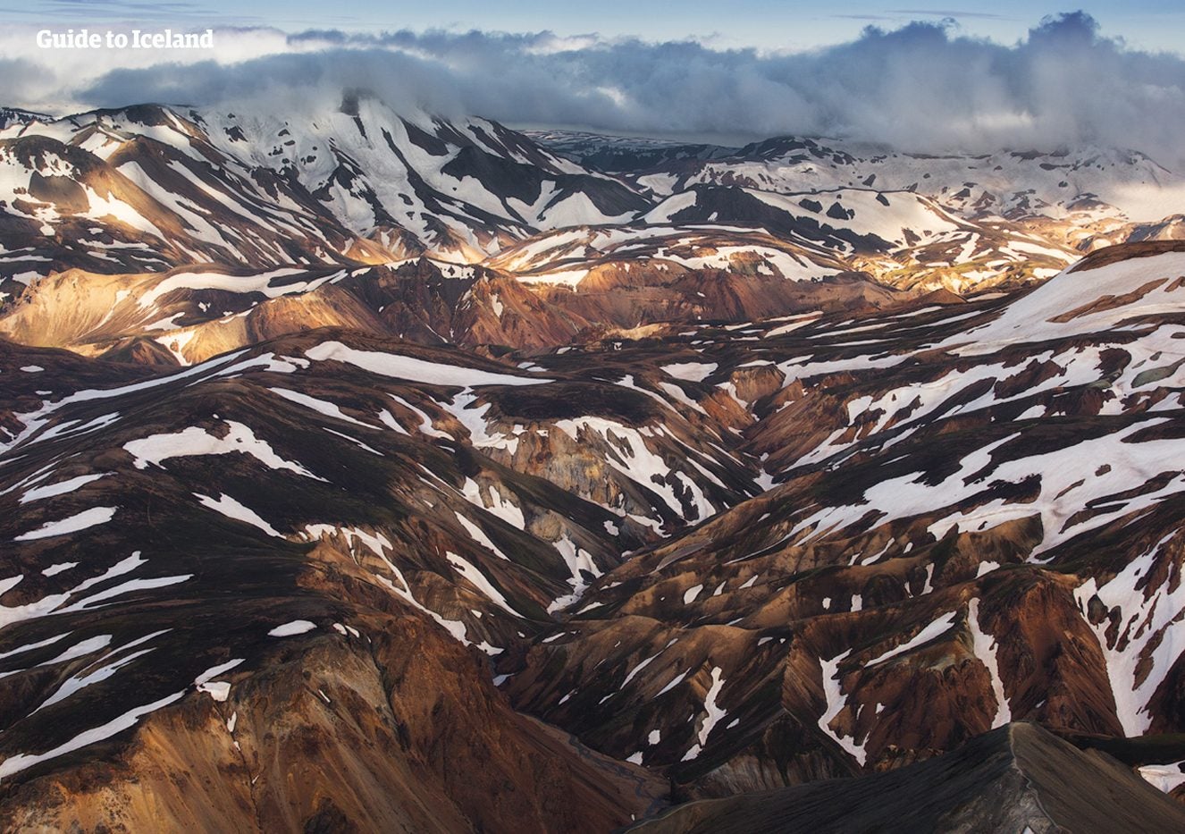 Sunlight breaks over the folded rhyolite mountains and valleys of Landmannalaugar in the Icelandic Highlands.
