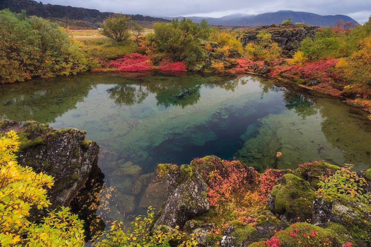 The church at Þingvellir and its houses reflect in still water at
