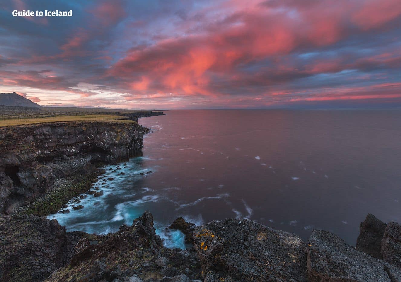 Pink clouds glow over the jagged coastline near Arnarstapi on the Snæfellsnes Peninsula, West Iceland.