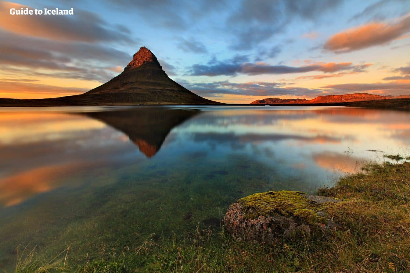 A golden sunset lights up Kirkjufell mountain mirrored in a calm pool on the Snæfellsnes Peninsula, West Iceland.