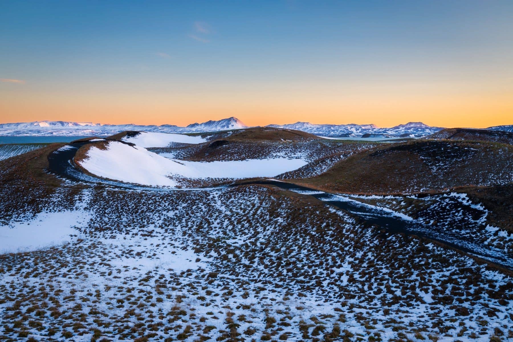 Snow-dusted Skútustaðagígar pseudo-craters catch the low sun beside Lake Mývatn in North Iceland.