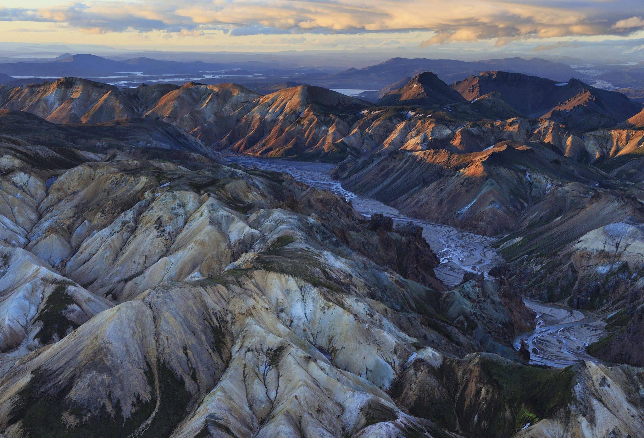 Braided glacial rivers wind between the multicoloured rhyolite mountains of the Icelandic Highlands, seen from above.