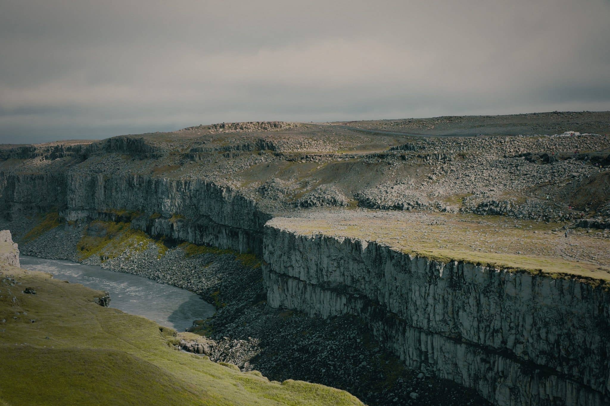 A glacial river carves through the sheer walls of a canyon in the Icelandic Highlands, viewed from above.