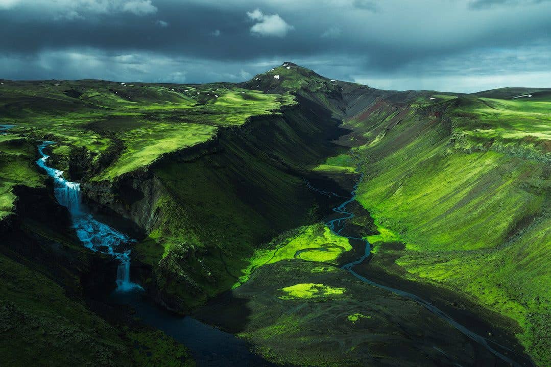 A waterfall spills into the lush green Eldgjá canyon, a volcanic rift in the Highlands of Iceland.