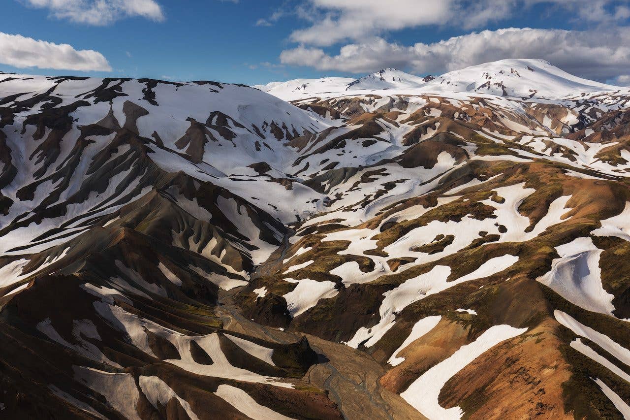 Snow lingers on the rugged brown mountains of the Fjallabak Nature Reserve in the Icelandic Highlands.