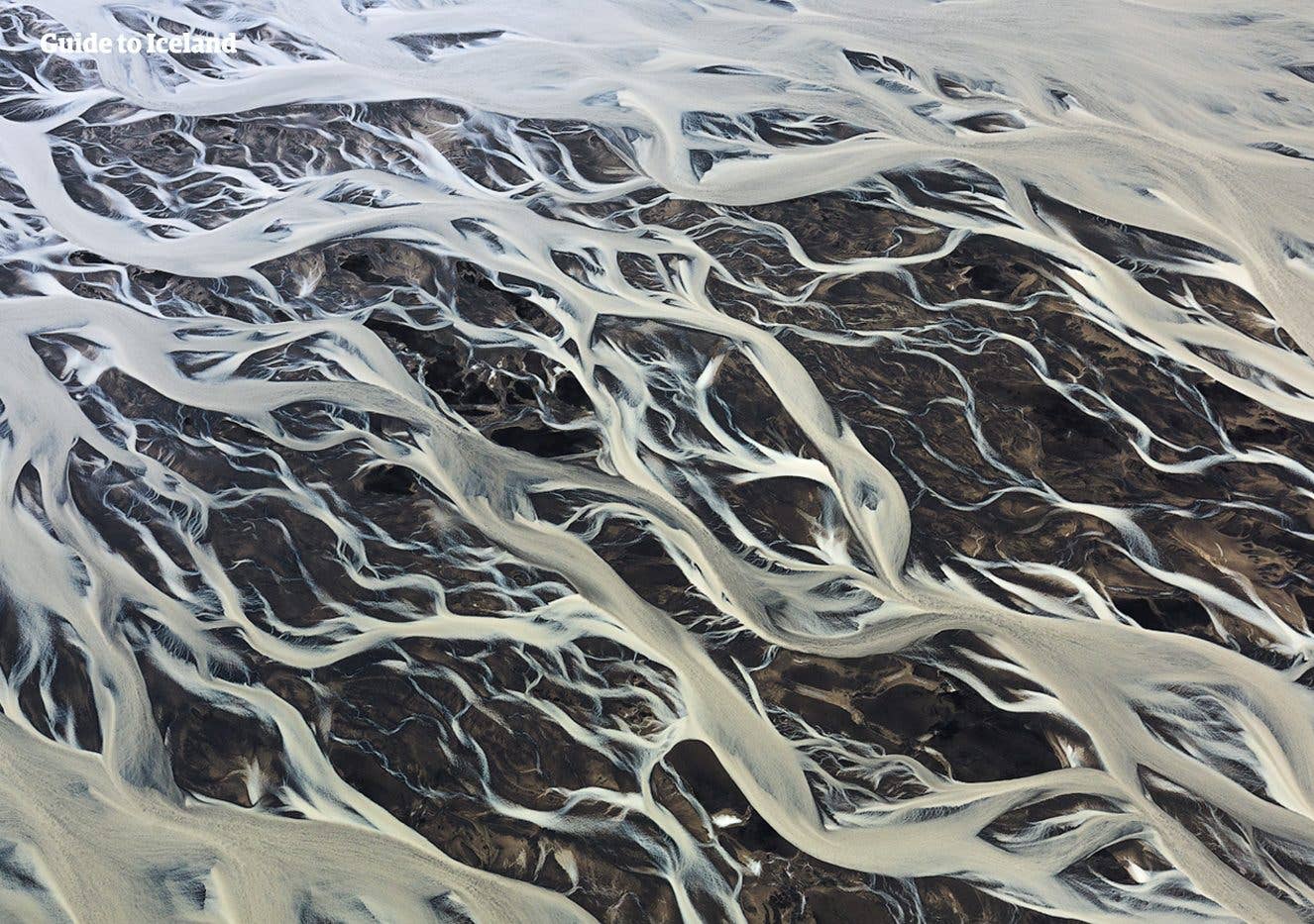 A braided glacial river fans out in silvery channels across the black sands of the Icelandic Highlands.