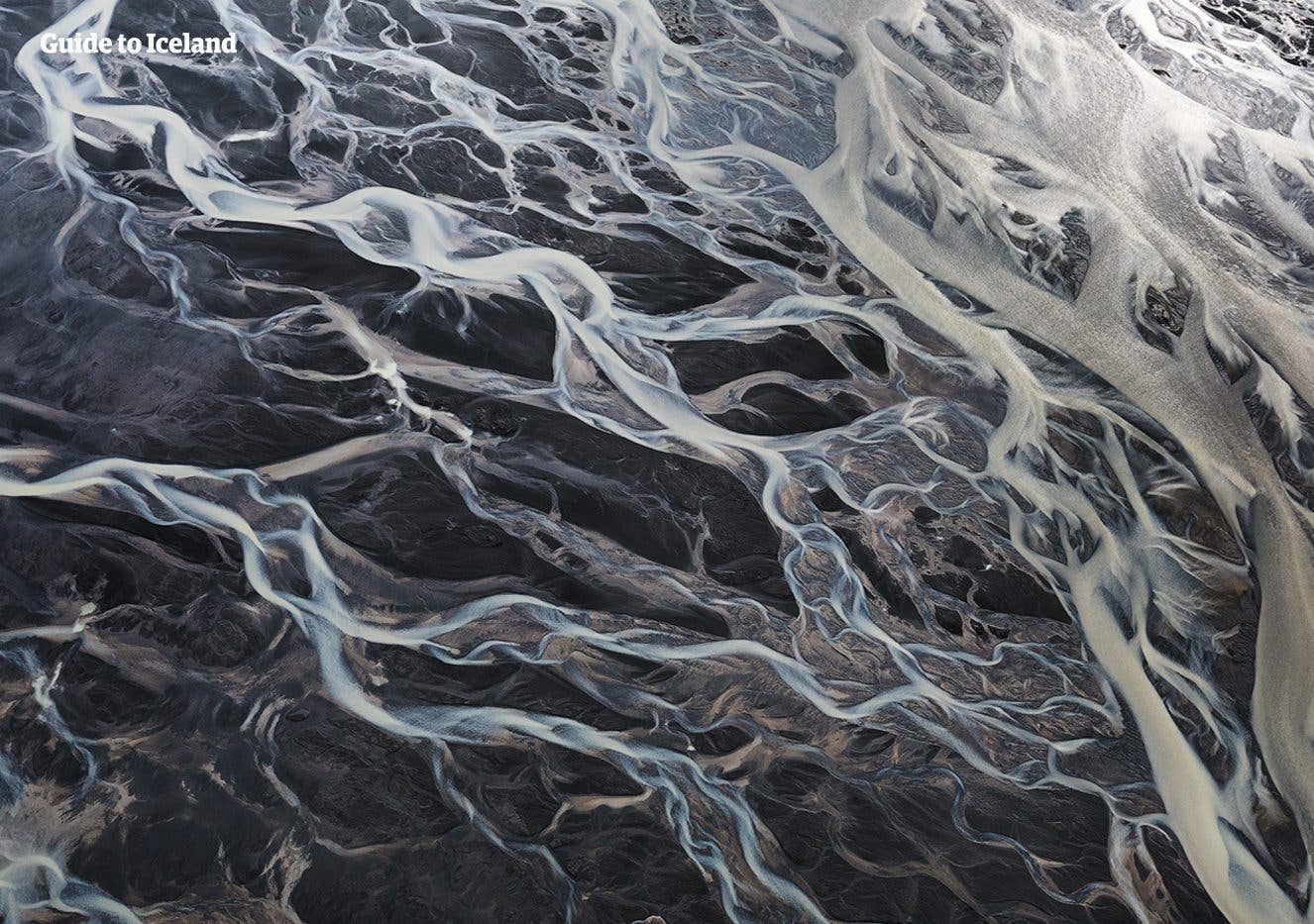 An aerial view of a braided glacial river spreading across dark Highland sands in Fjallabak, Iceland.