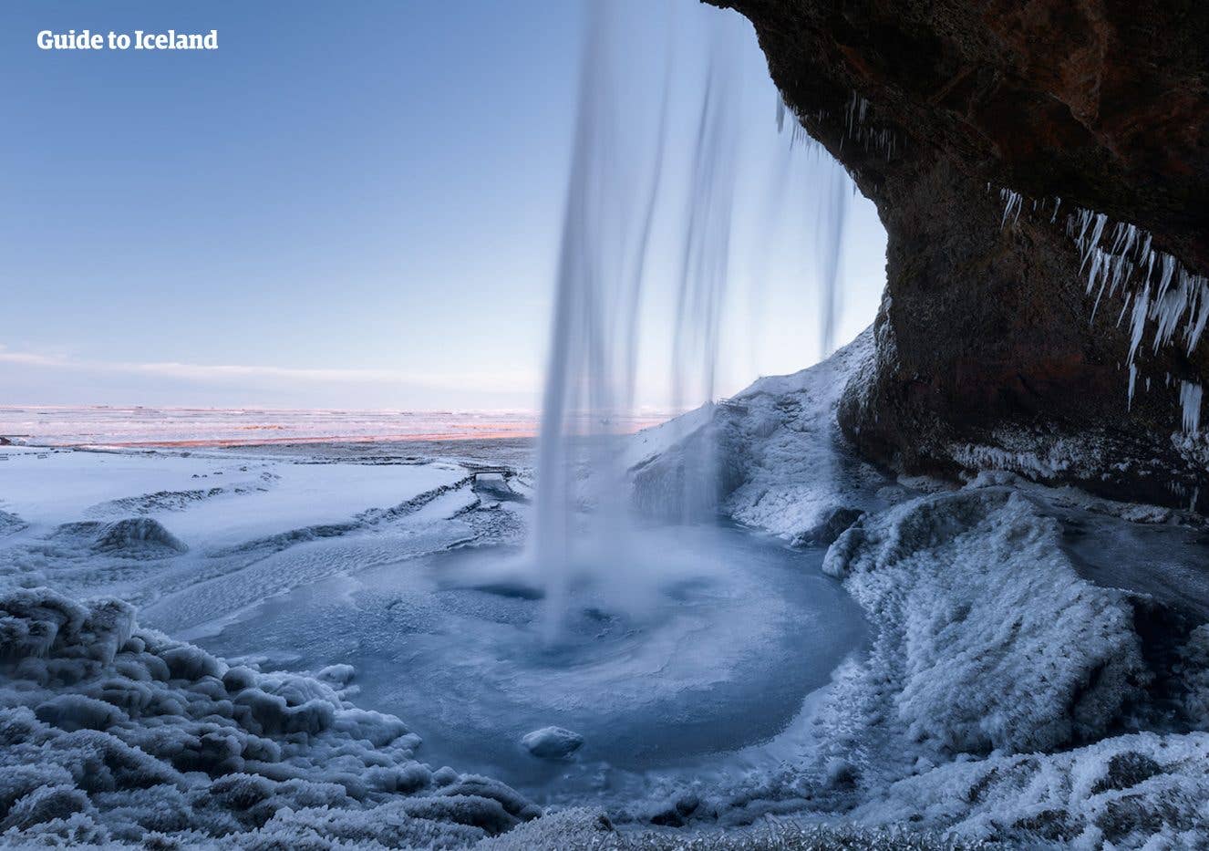 Seljalandsfoss, the waterfall you can walk behind, framed by ice and snow on the south coast of Iceland.