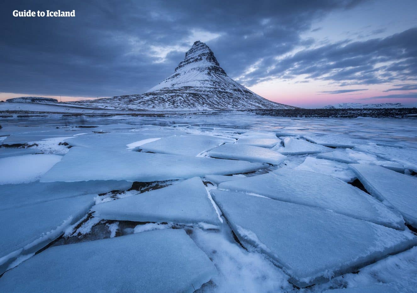 Kirkjufell mountain rises above a lake broken into sheets of ice in winter on the Snæfellsnes Peninsula, Iceland.