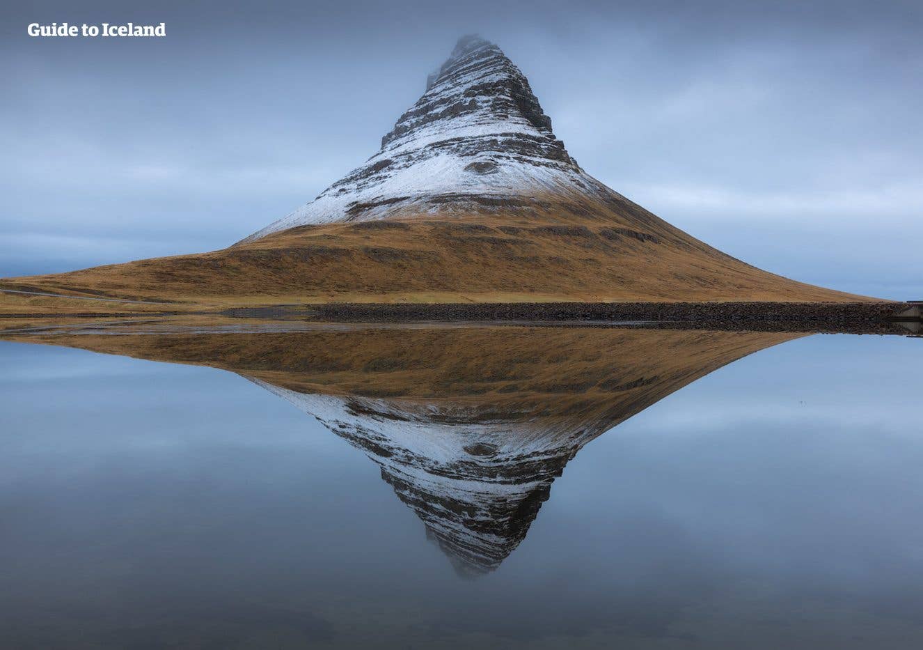 The snow-capped Kirkjufell mountain mirrors in still water in winter on the Snæfellsnes Peninsula, Iceland.