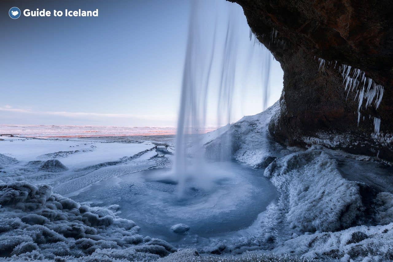 The path behind Seljalandsfoss waterfall glazes with ice on a winter evening in South Iceland.