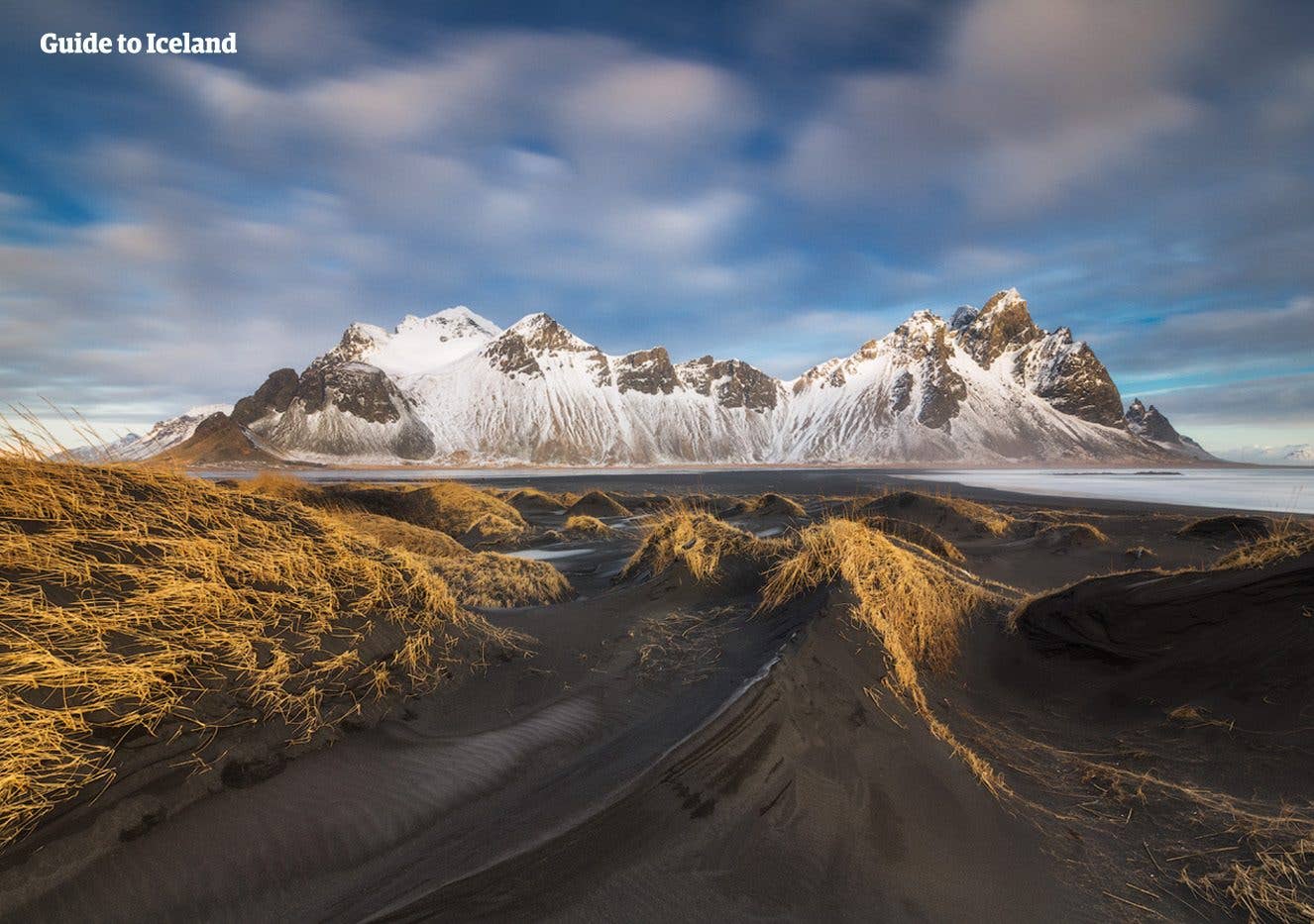 The snowy peaks of Vestrahorn rise above black-sand dunes at Stokksnes in winter, southeast Iceland.