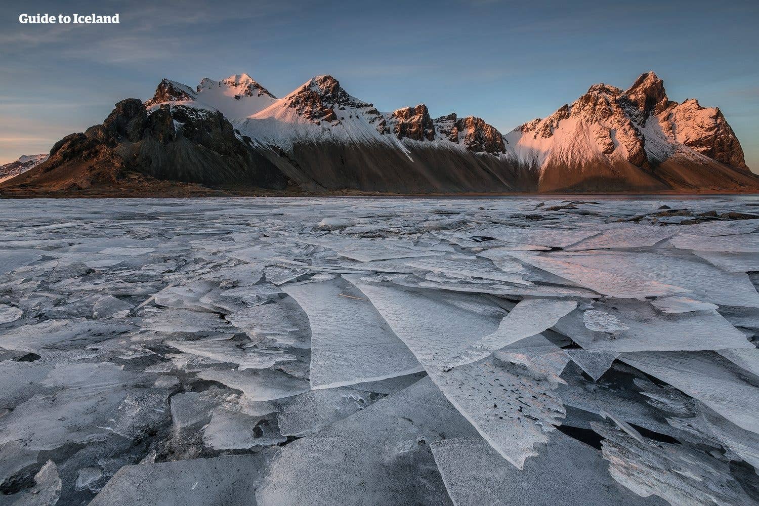 Sheets of ice cover the flats beneath the snowy Vestrahorn massif at Stokksnes, southeast Iceland.