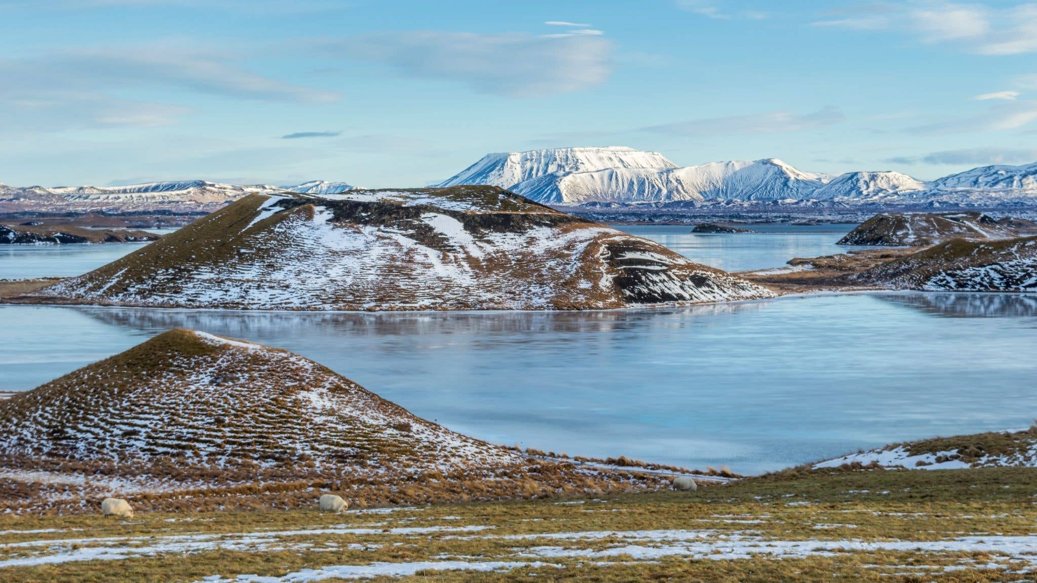 Snow dusts the pseudo-craters beside Lake Mývatn under a bright winter sky in North Iceland.