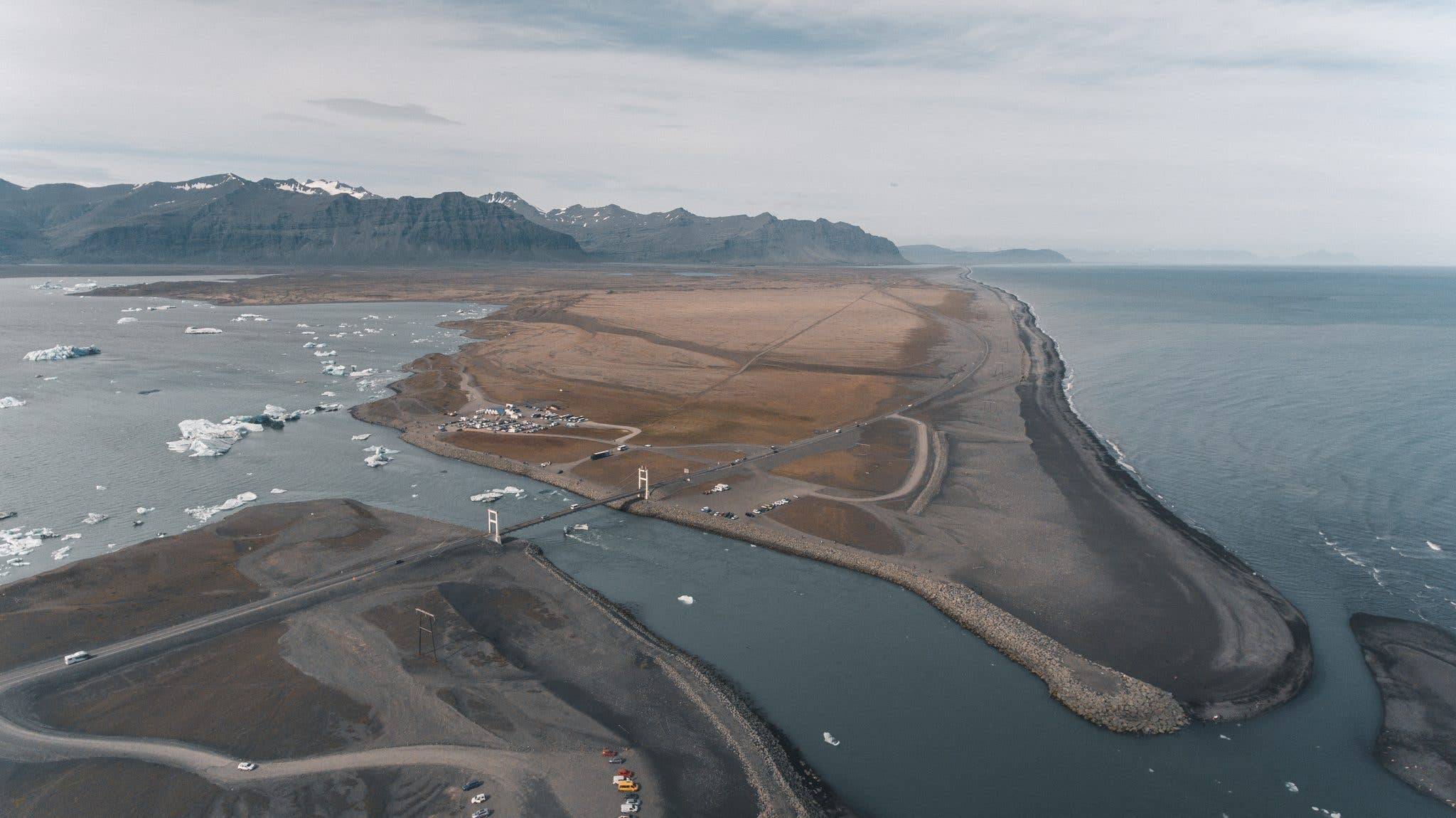 An aerial view of a black-sand spit reaching into a glacial lagoon in southeast Iceland.