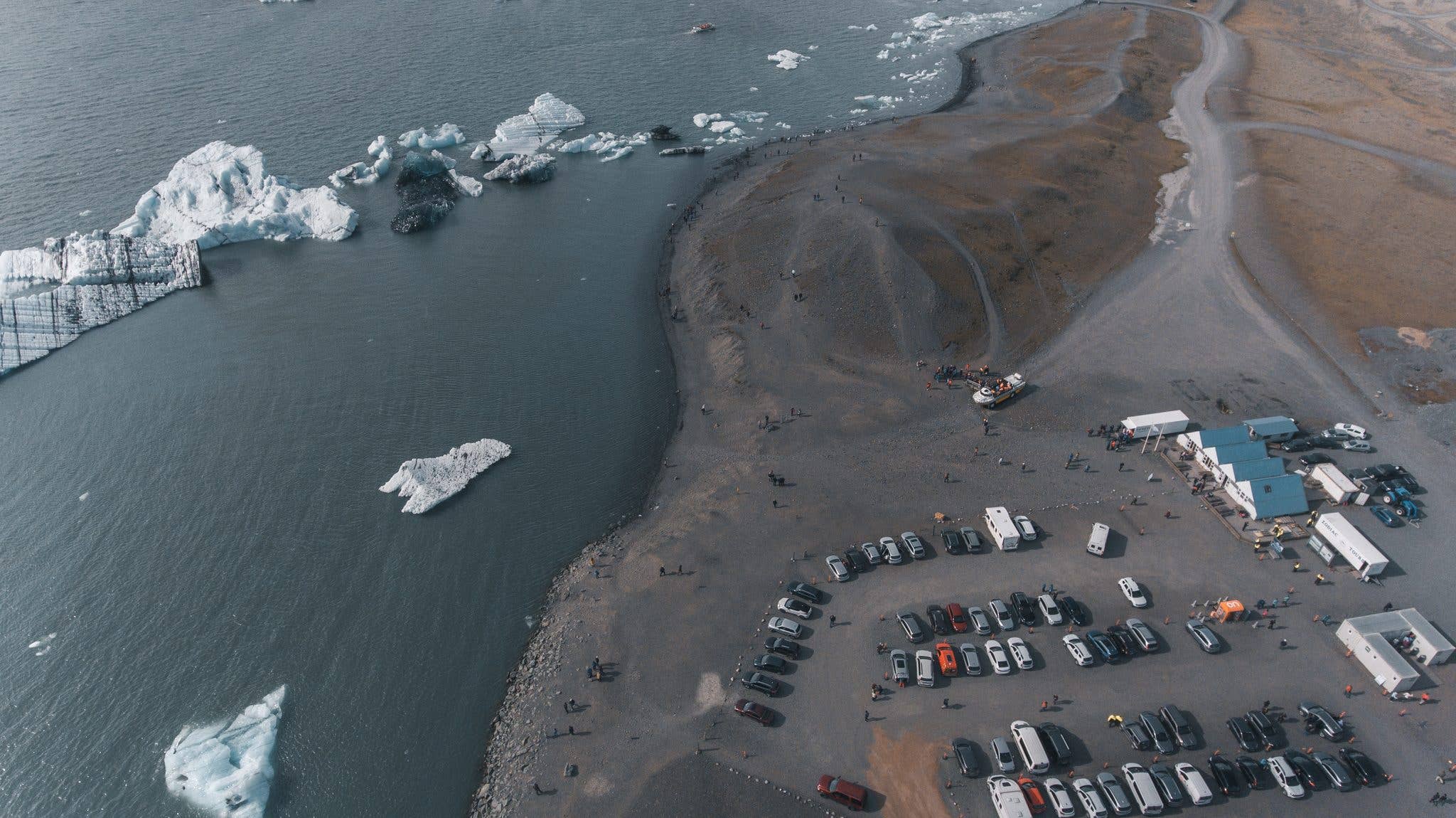 Icebergs and parked cars seen from above at the edge of the Jökulsárlón glacier lagoon in southeast Iceland.