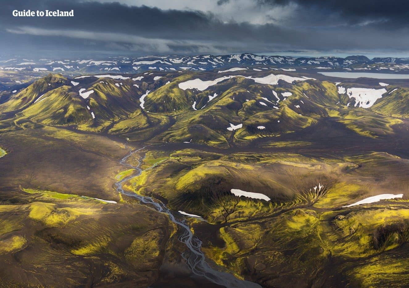 Green, moss-covered mountains and a glacial river seen from above in the Fjallabak Highlands of Iceland.