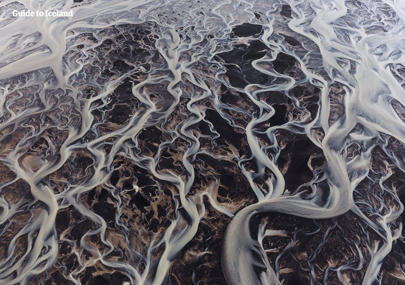 Silvery glacial rivers braid across dark Highland sands in Fjallabak, Iceland, seen from above.