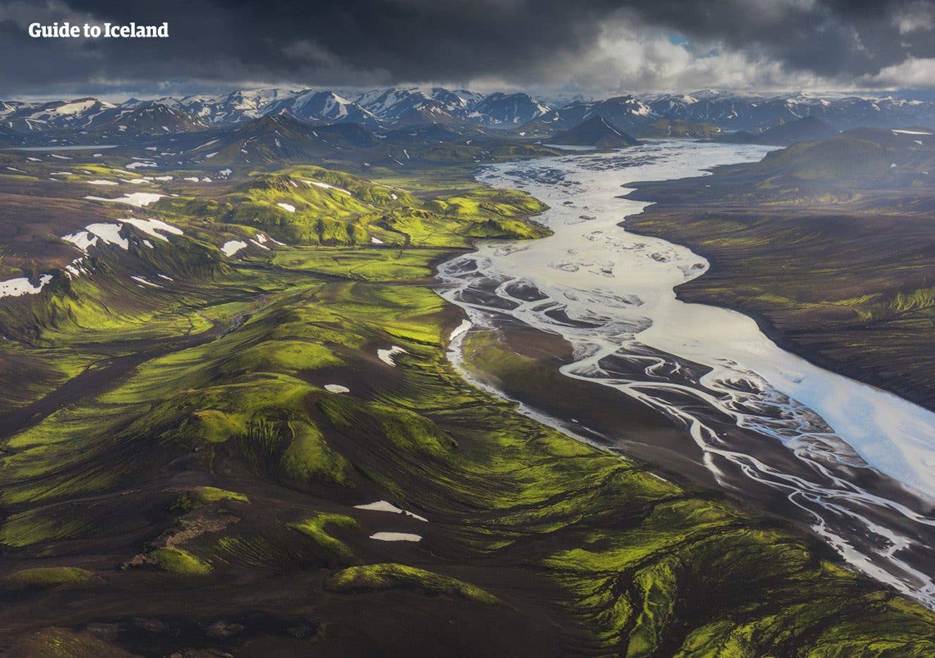 A glacial river winds through green rhyolite mountains in the Fjallabak Highlands of Iceland.
