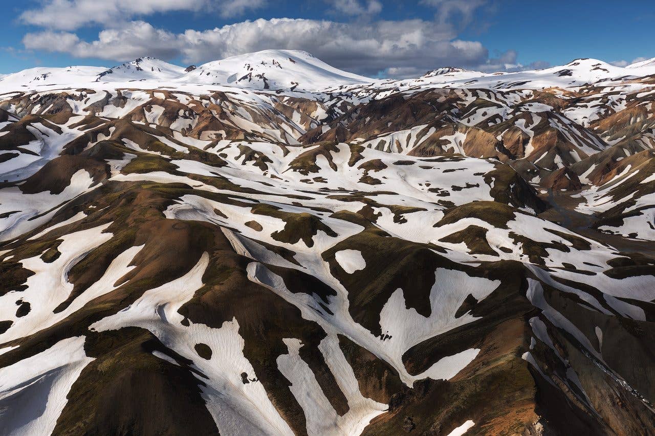 Snow patches streak the rugged rhyolite mountains of the Icelandic Highlands, seen from above.