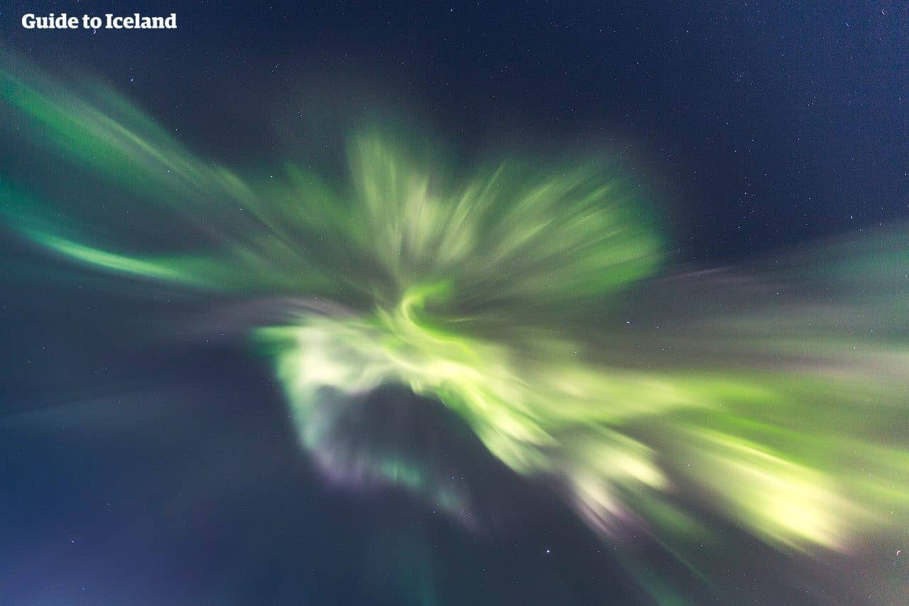 Bright green northern lights swirl across the night sky over Iceland.