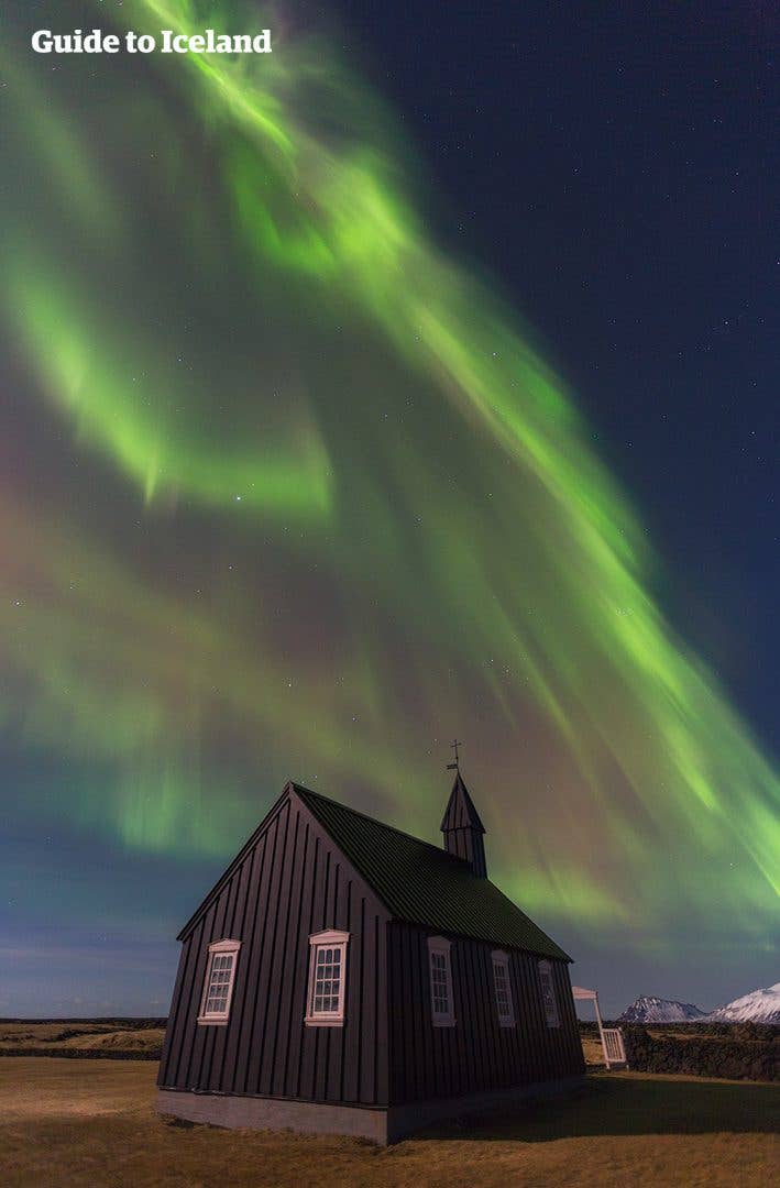 The northern lights glow above the black Búðakirkja church on the Snæfellsnes Peninsula in West Iceland.