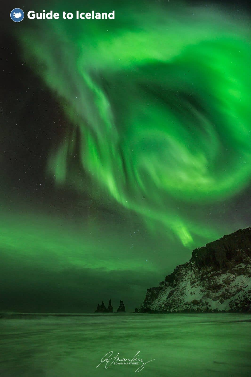 The aurora borealis lights the sky over the Reynisdrangar sea stacks on Iceland south coast.