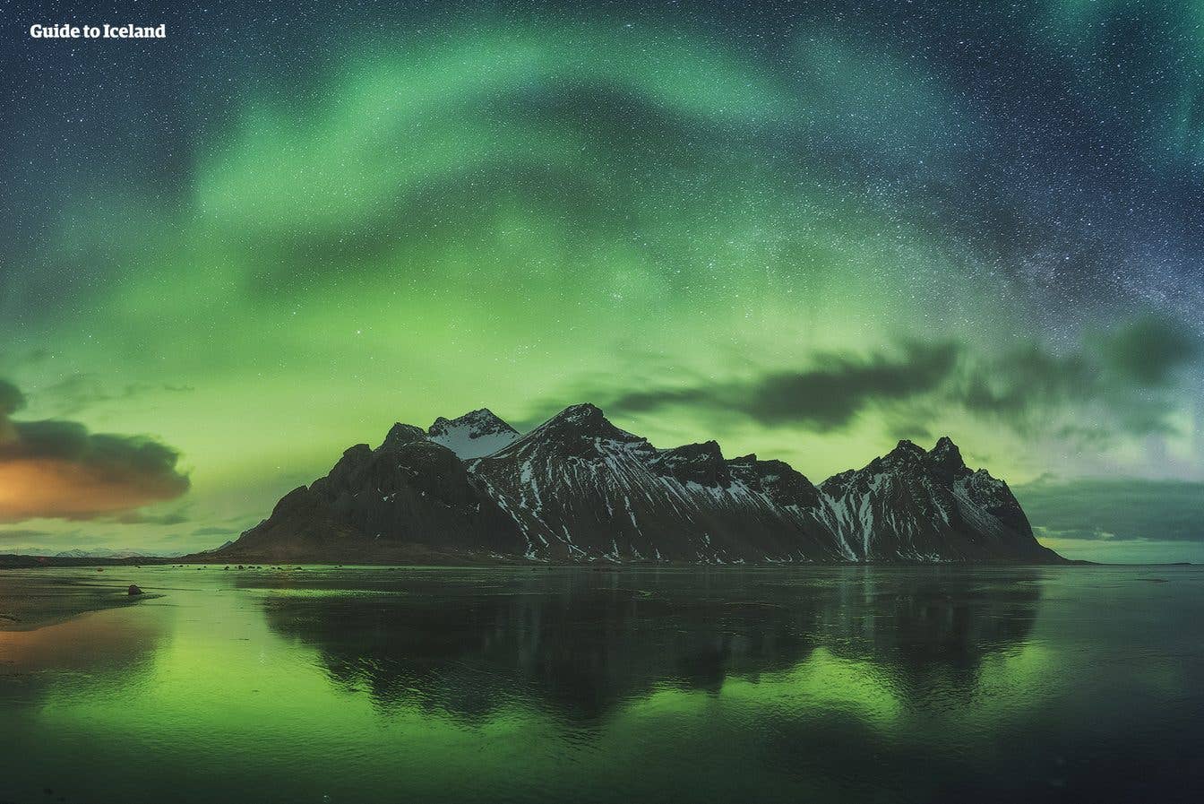 The northern lights glow above Vestrahorn mountain, mirrored in the wet sand at Stokksnes in Southeast Iceland.