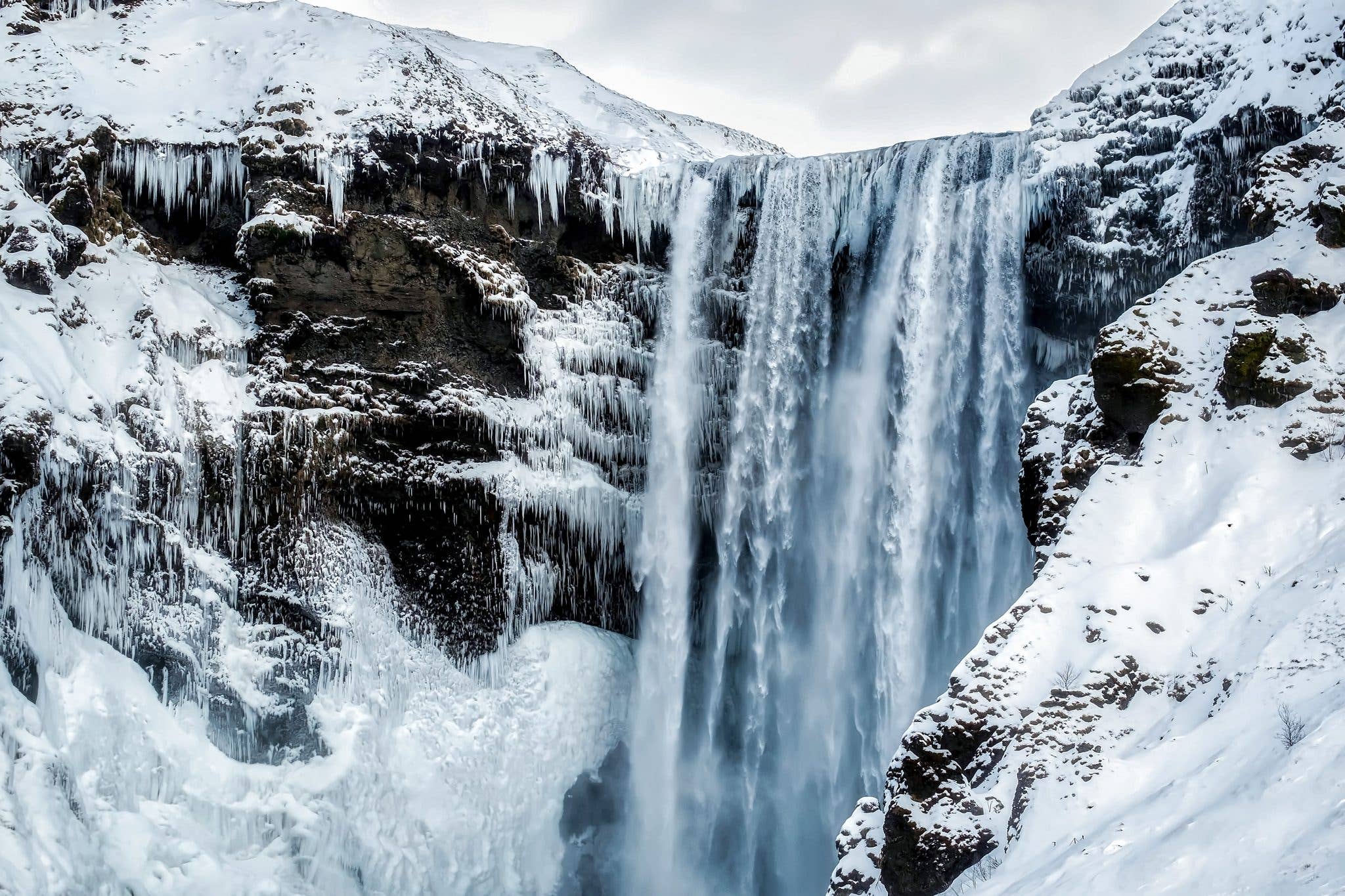 The Skógafoss waterfall thunders past snow-covered banks in winter in South Iceland.