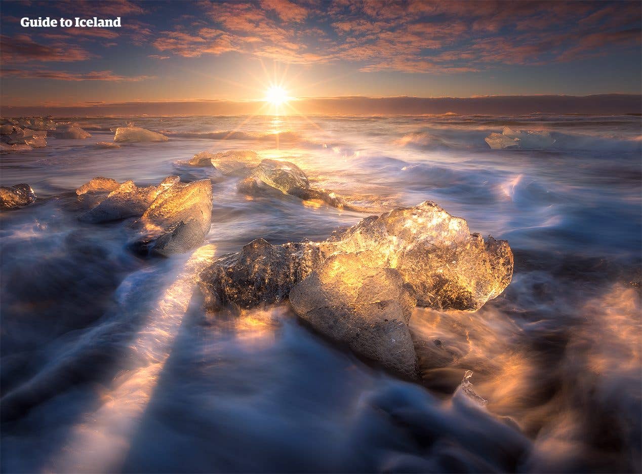 Clear blocks of glacier ice lie on the snowy black shore of the Diamond Beach in Southeast Iceland.