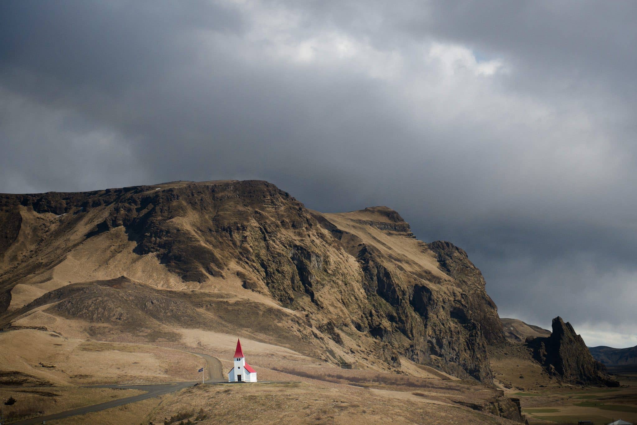 The red-roofed Víkurkirkja church stands on a hill above the village of Vík in South Iceland.