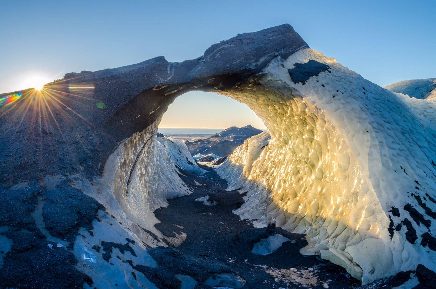 Sunlight glows through an ice arch on the Sólheimajökull glacier in South Iceland.