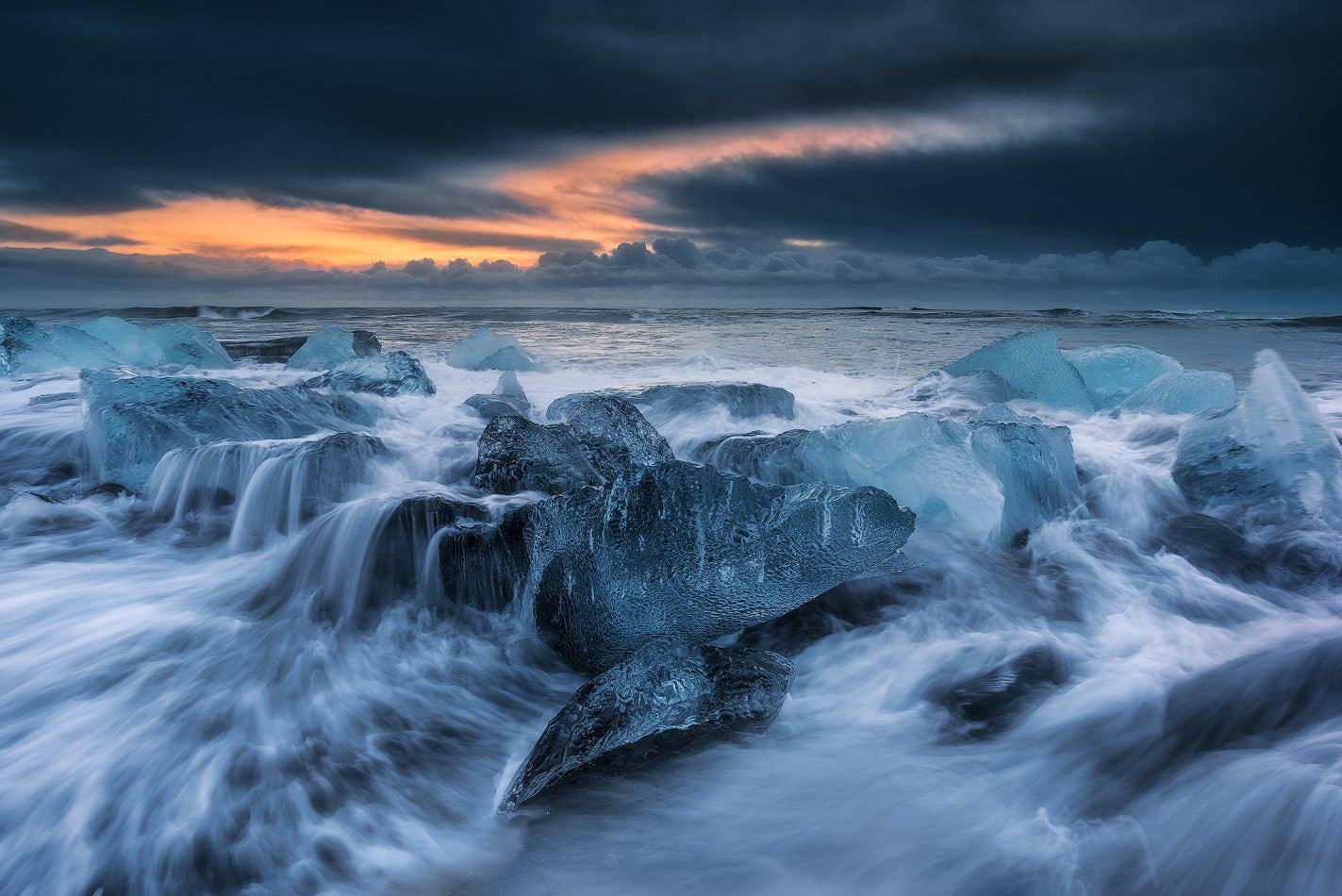 Blocks of glacier ice glow at sunset on the black sand near Jökulsárlón in Southeast Iceland.