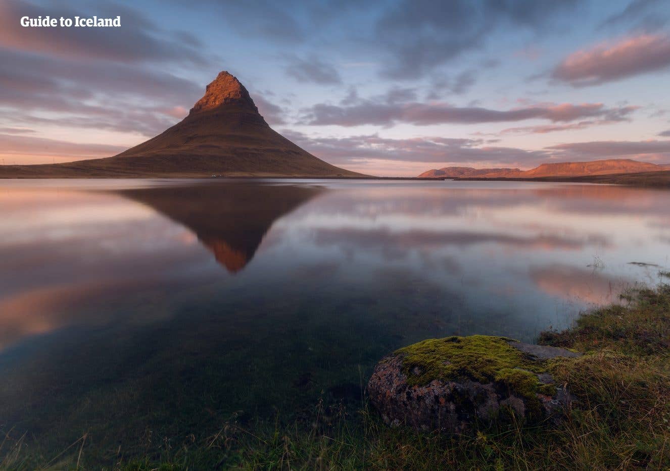 Kirkjufell mountain mirrors in calm water at sunset on the Snæfellsnes Peninsula, Iceland.