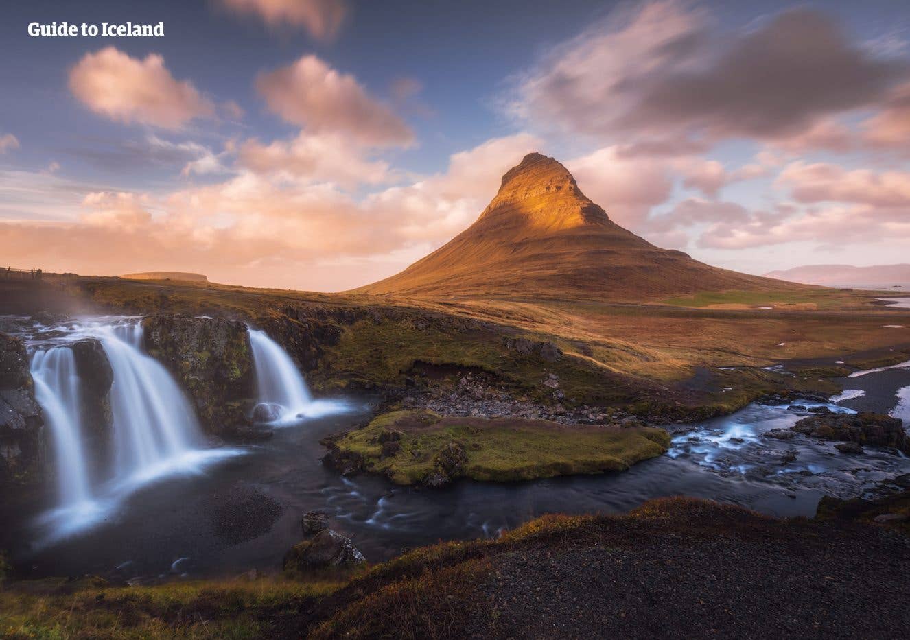 The Kirkjufellsfoss waterfall streams below the pointed Kirkjufell mountain in West Iceland.