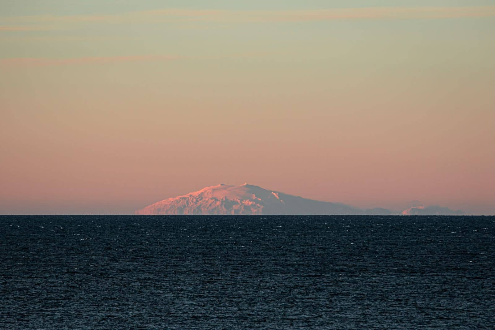 The snow-capped Snæfellsjökull glacier volcano rises across the sea in West Iceland.