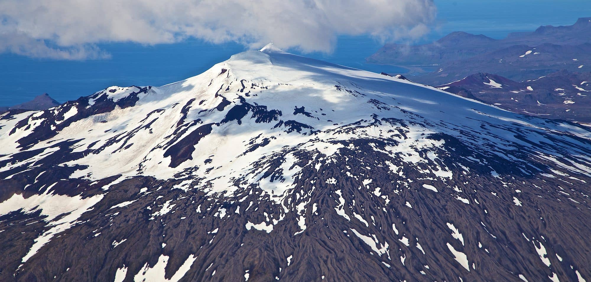 A steep, layered pyramid mountain rises under the evening light in West Iceland.