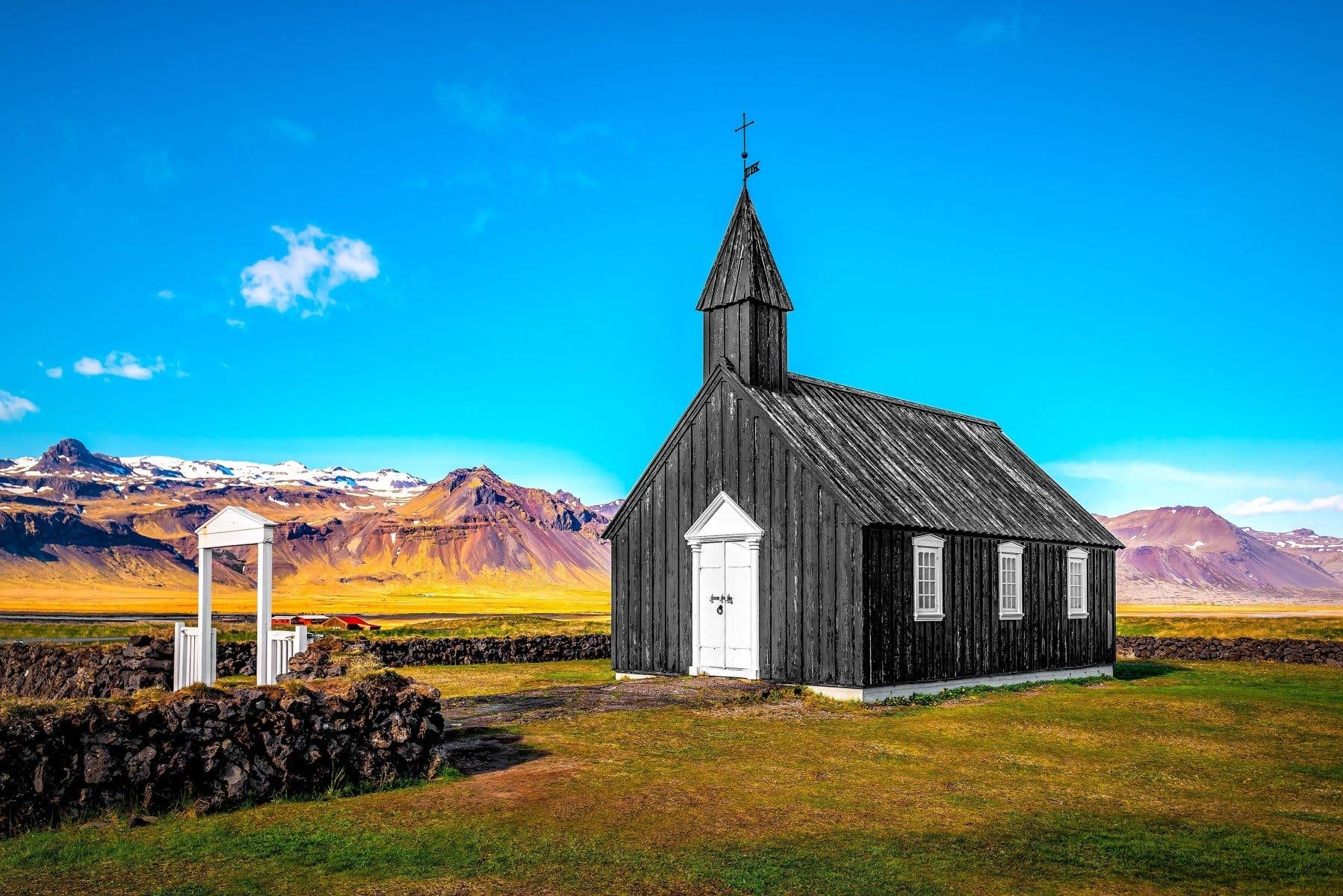 The black Búðakirkja church stands alone under a blue sky on the Snæfellsnes Peninsula in West Iceland.