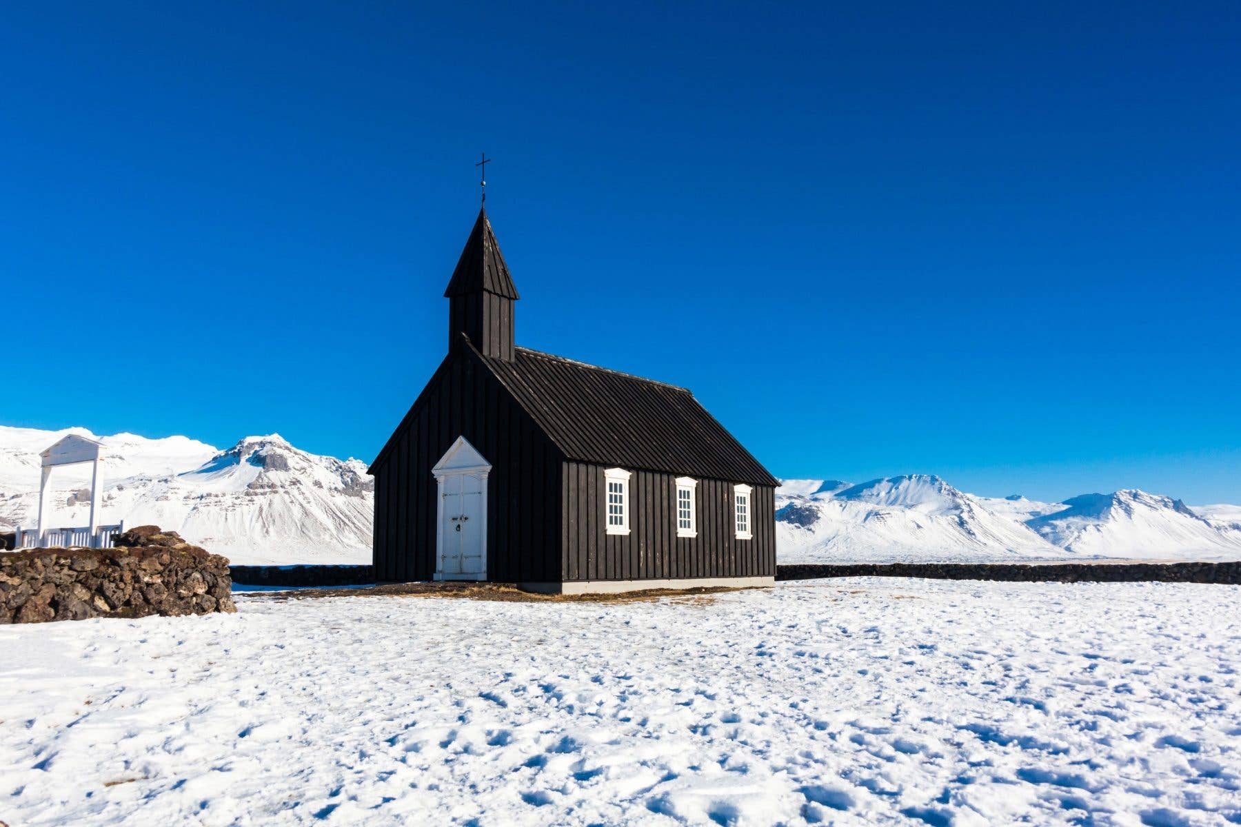 Snow surrounds the black Búðakirkja church on the Snæfellsnes Peninsula in West Iceland.