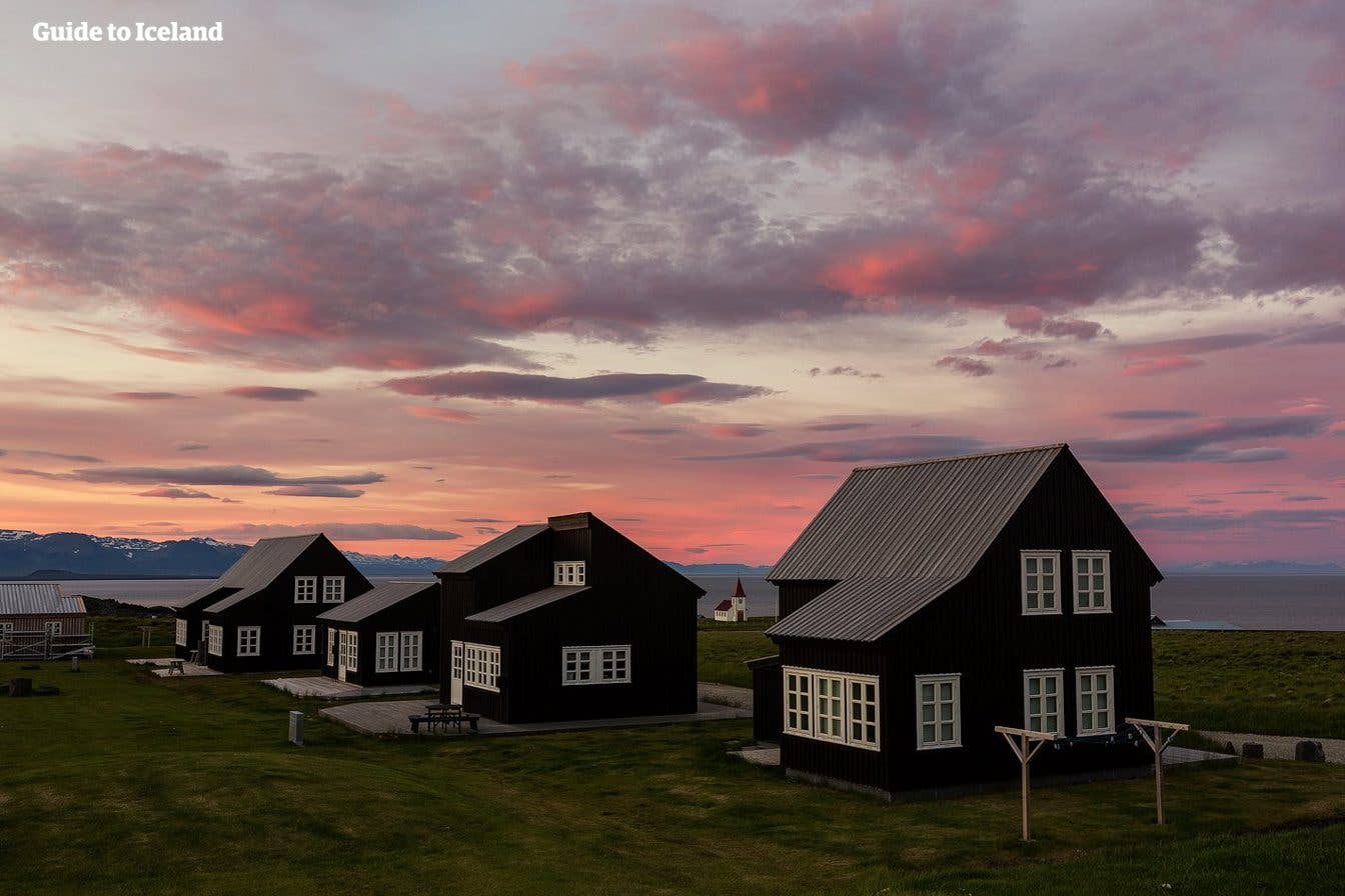 Black-timbered houses sit by the sea at sunset in the village of Hellnar on the Snæfellsnes Peninsula, Iceland.