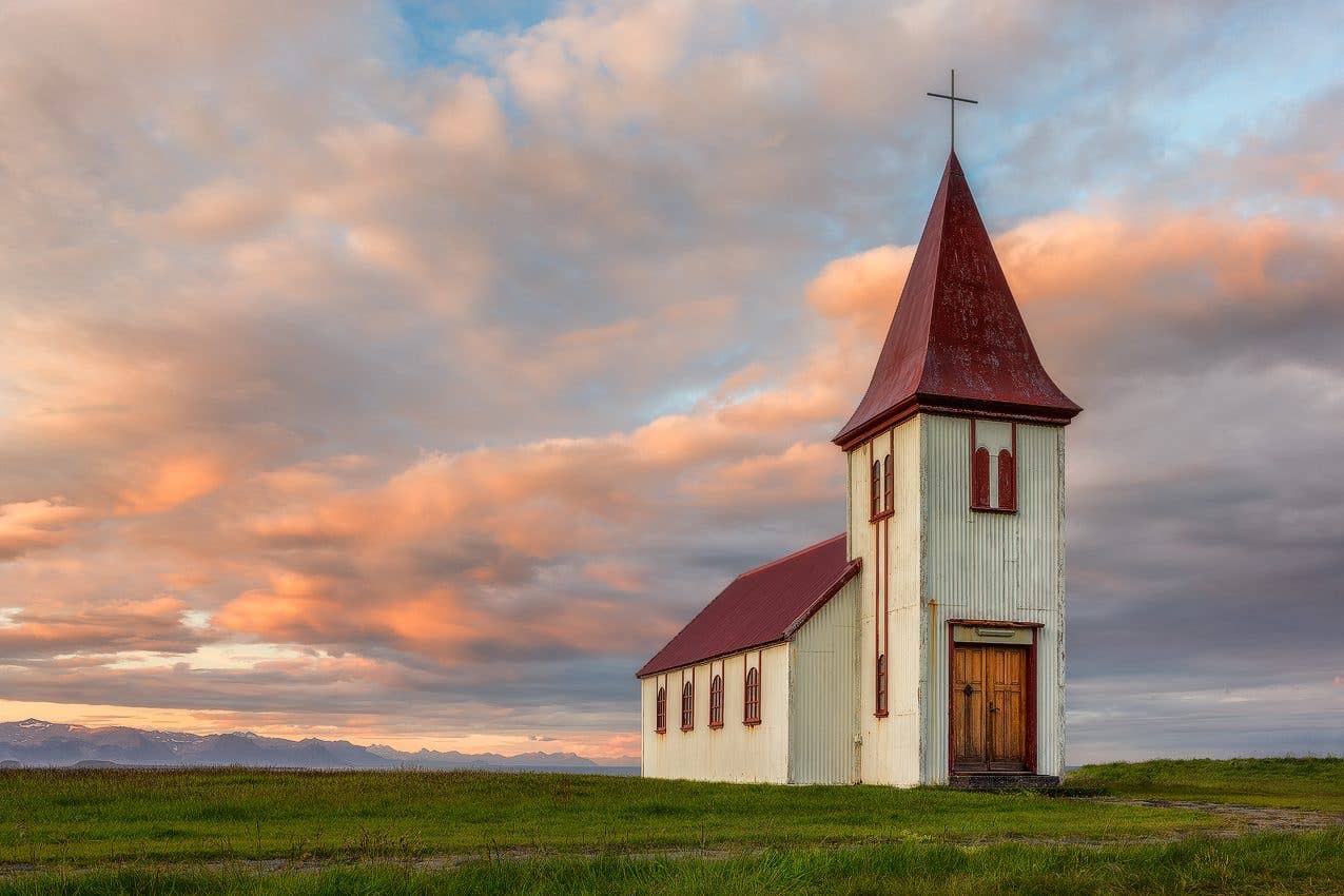 The white Hellnakirkja church stands below the mountains near Hellnar on the Snæfellsnes Peninsula, Iceland.