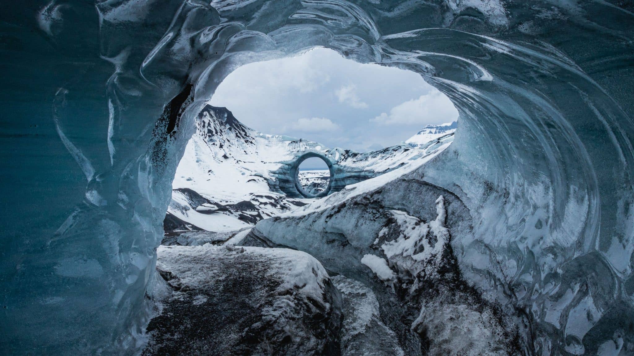 Daylight streams through the entrance of the Katla ice cave beneath a glacier in South Iceland.