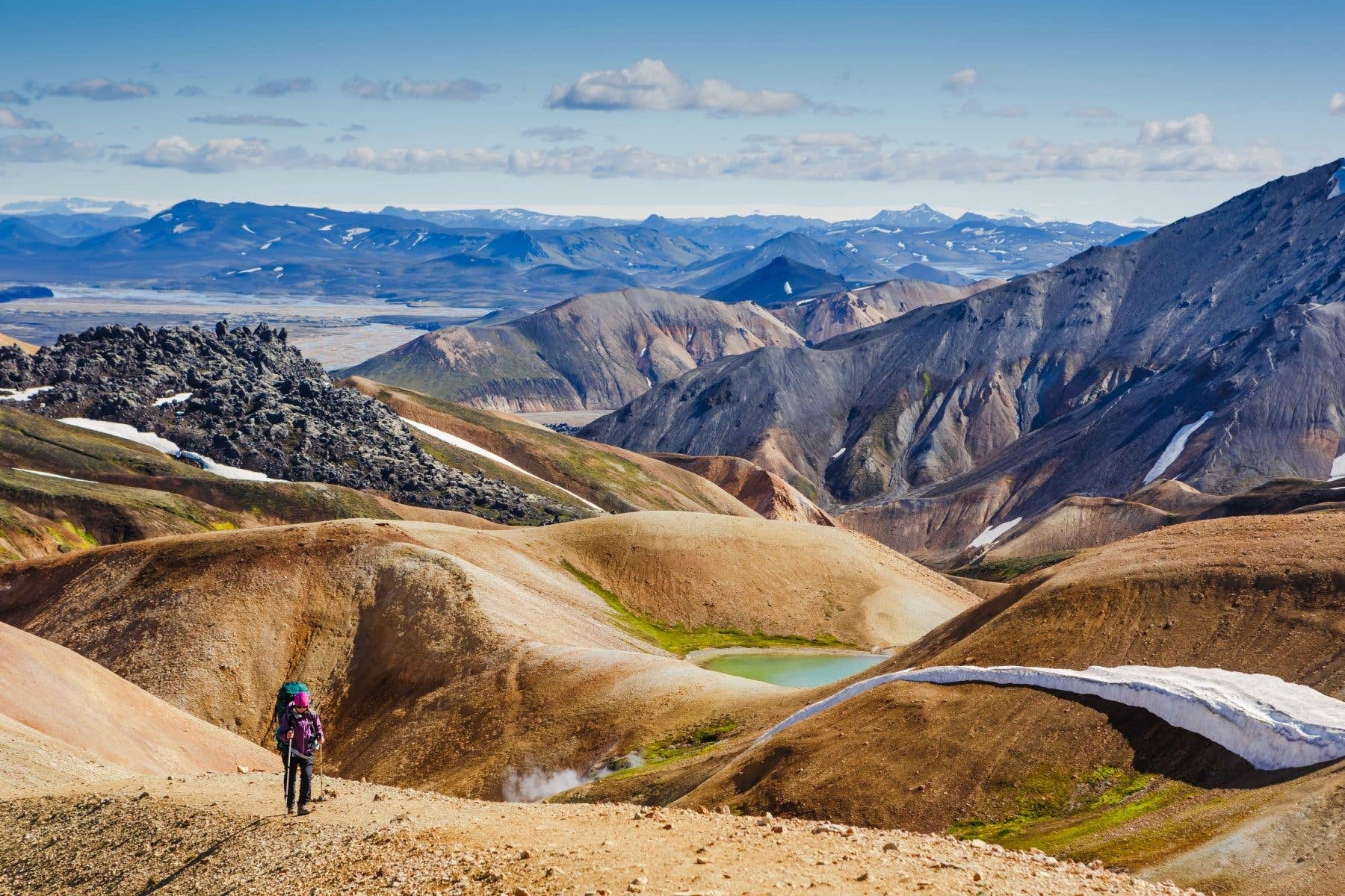 A hiker walks through the colourful rhyolite mountains of Landmannalaugar in the Icelandic highlands.