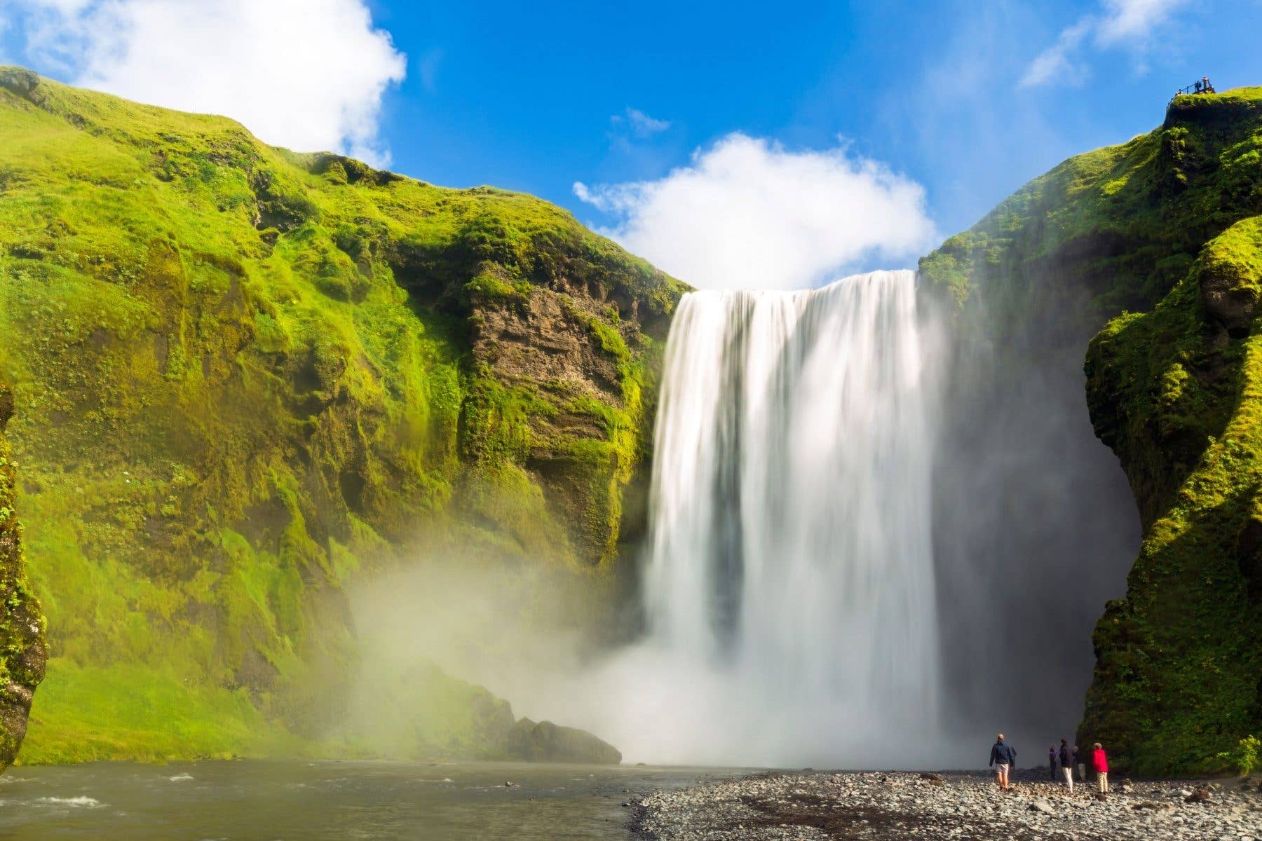 The Skógafoss waterfall thunders over a green cliff on the south coast of Iceland.