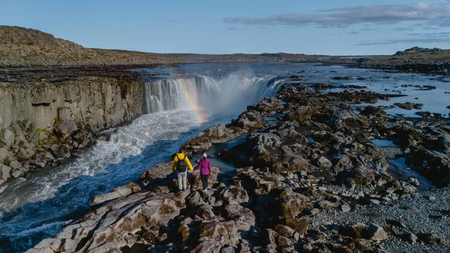 Hikers viewing Dettifoss Waterfall in Jokulsargljufur Canyon.