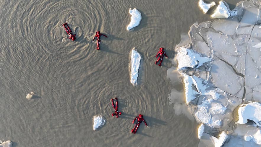 Travelers in thermal flotation suits drifting among icebergs during the ice floating experience at Fjallsarlon Glacier Lagoon in Southeast Iceland.