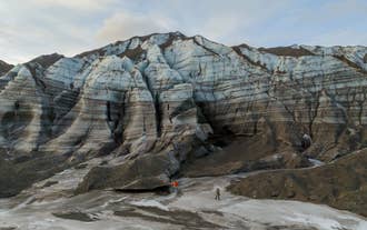 Layered ash bands stripe the towering ice wall at the Katla Glacier outlet near Vik in South Iceland.